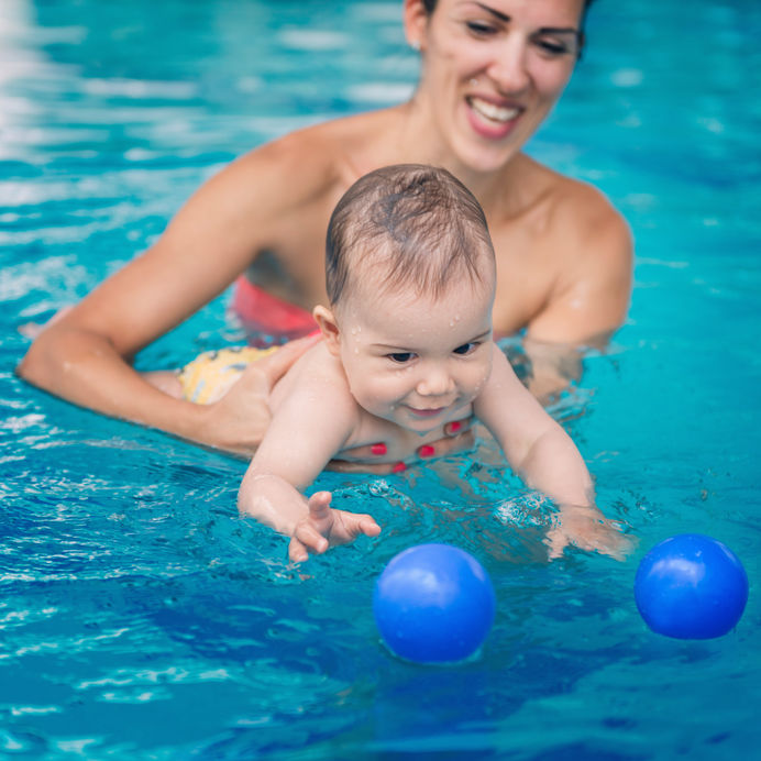 Baby boy swimming with mother