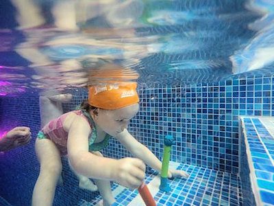 toddler retrieving dive sticks underwater