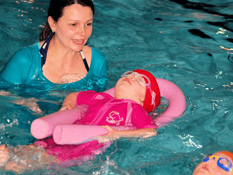 toddler swimming back float with instructor