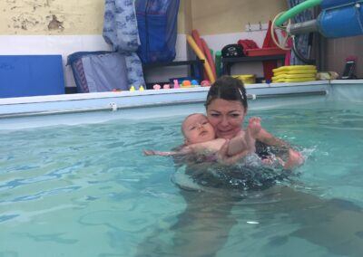 Baby kicking her legs and swimming on back with Mummy