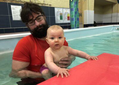 Baby holding onto large swimming float