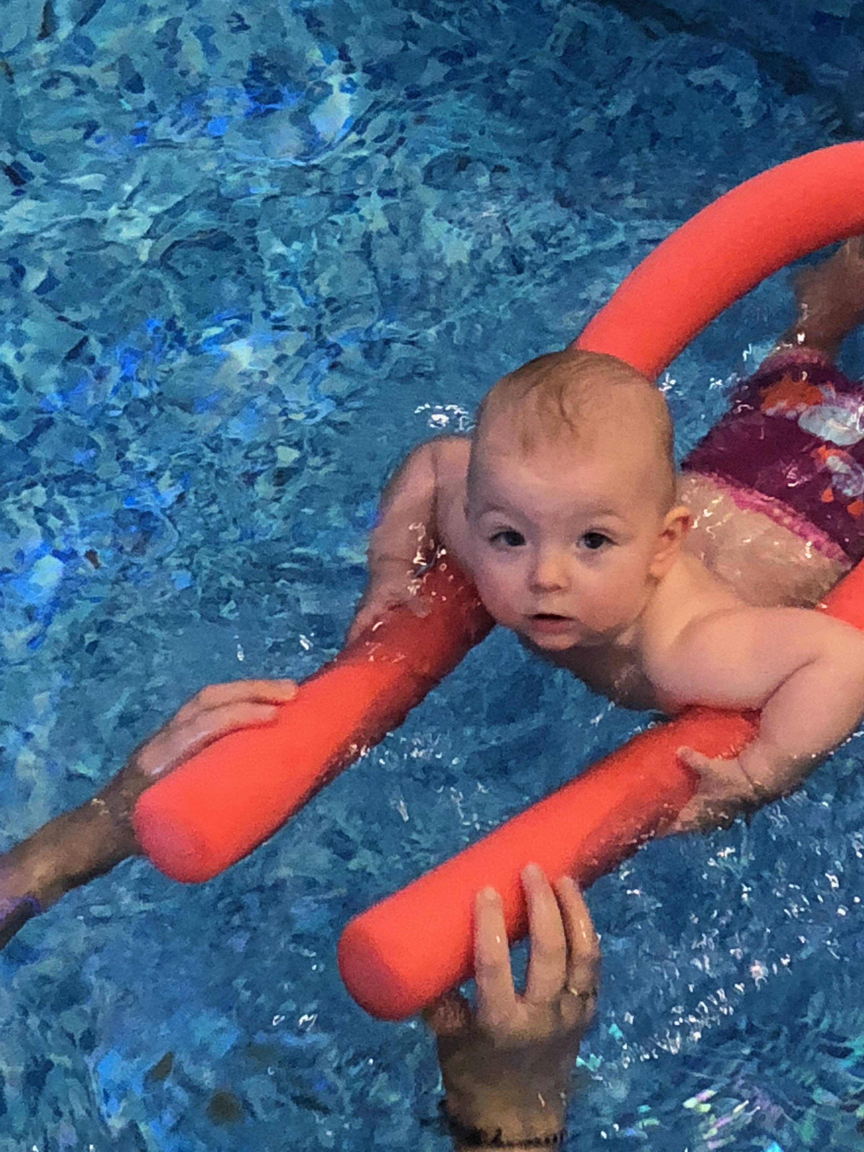 baby swimming with pool noodle