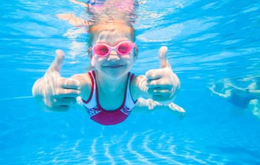 child under water giving thumbs up
